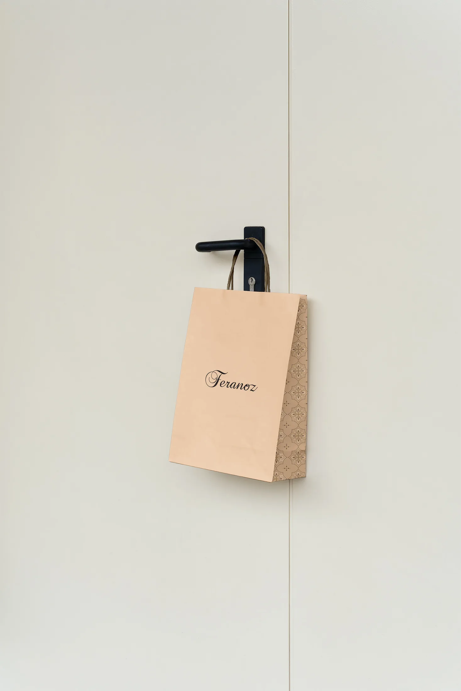 A small kraft Feranoz paper bag hanging from a black hook